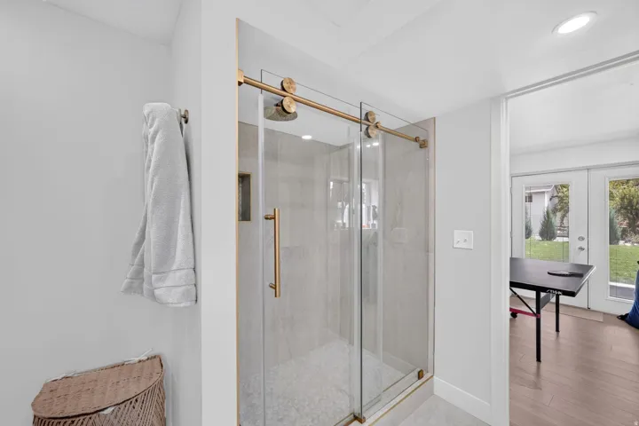 Glass-enclosed shower with gold-tone hardware, a rain showerhead, and tile-finish walls