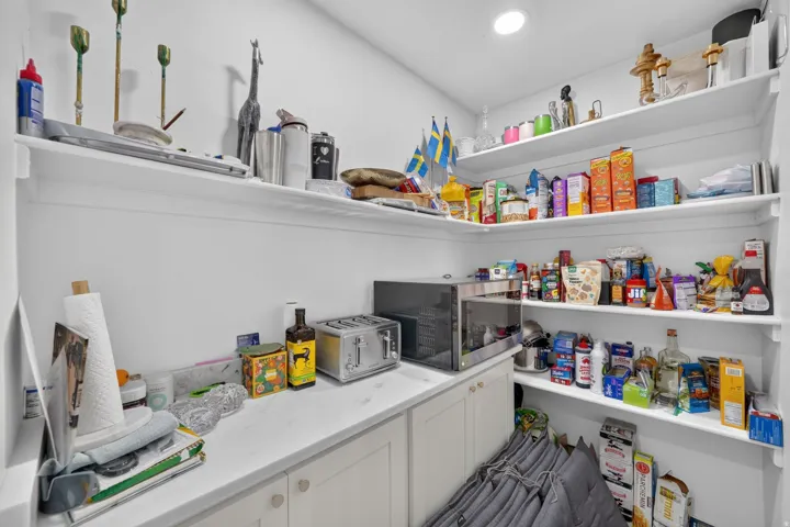 Integrated pantry featuring extensive open shelving, built-in lower cabinetry, and recessed lighting