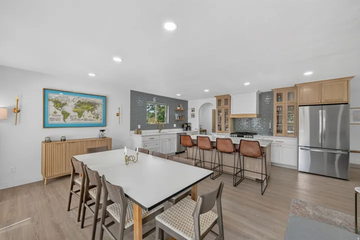 Open-concept kitchen and dining area featuring wood-finish flooring, recessed lighting, and a kitchen island with seating