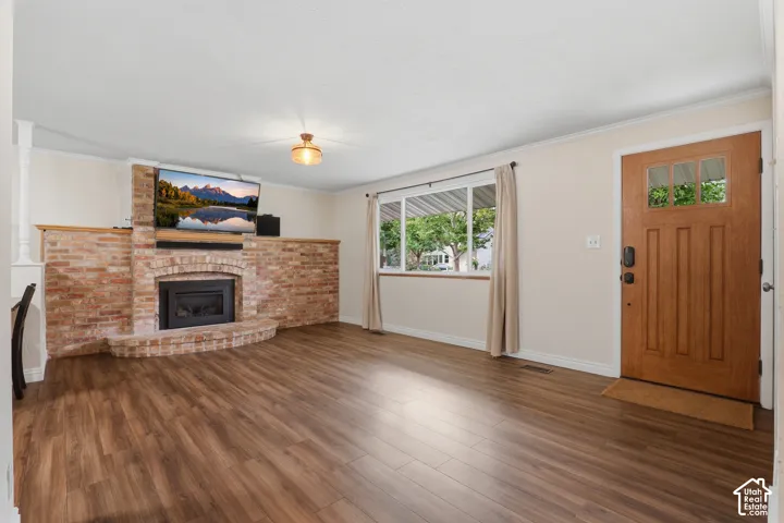 Brick fireplace with an arched firebox, wood-finish flooring, and a solid wood entry door with glass panels