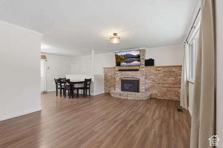 Wood-finish flooring throughout, brick fireplace with a hearth and mantel, and white trim