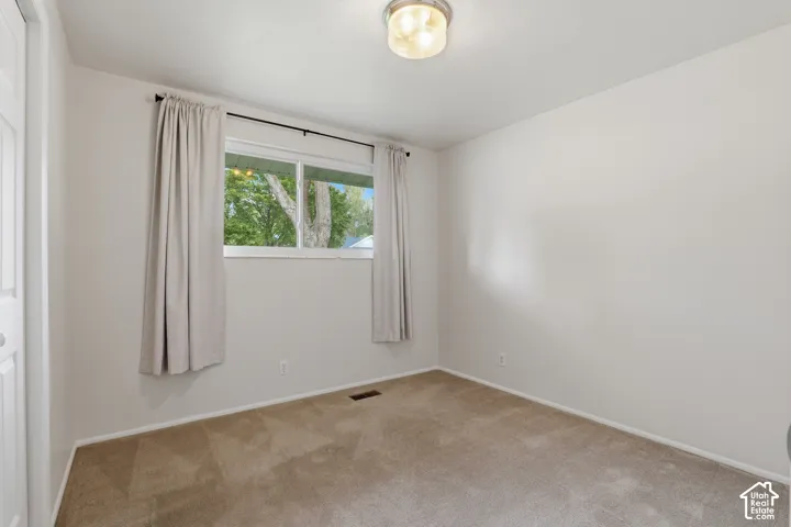 Neutral wall paint, window with exterior foliage, and a flush mount ceiling light