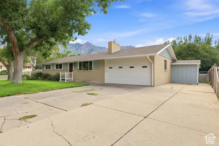 Brick exterior with a prominent two-car garage, front lawn, and visible mountain backdrop
