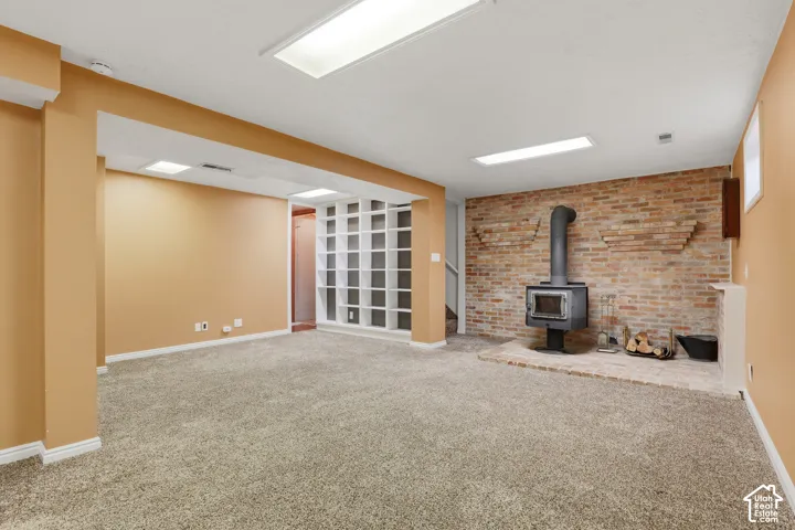 Wood-burning stove set against an exposed brick wall with built-in shelving and recessed lighting