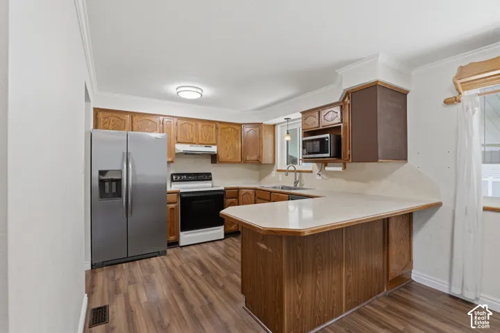 Kitchen featuring wood-finish flooring, stainless steel side-by-side refrigerator, white range with overhead exhaust, and wood cabinetry with crown molding