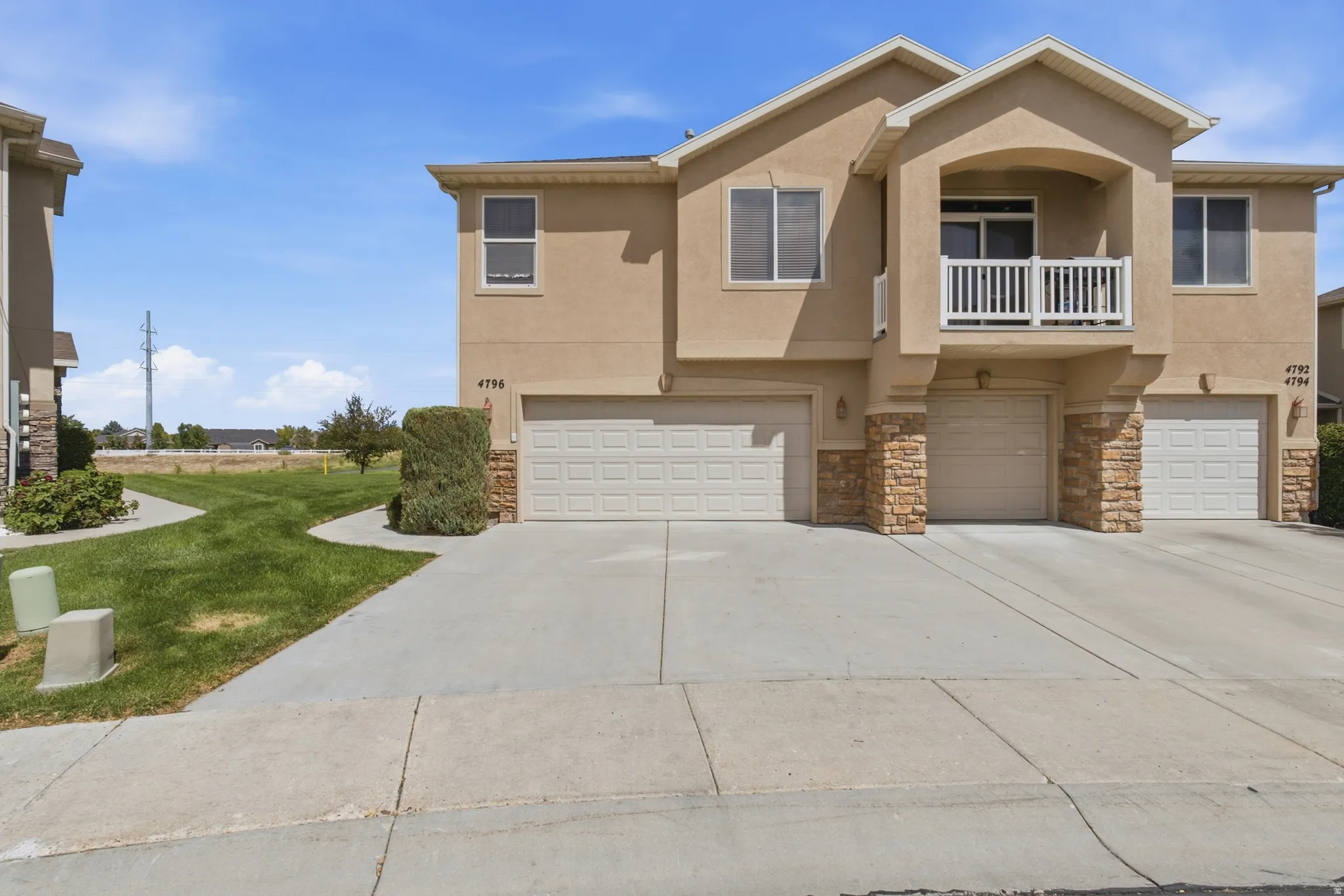 Stucco exterior with stone accents, multiple garage bays, and a private balcony with white railings