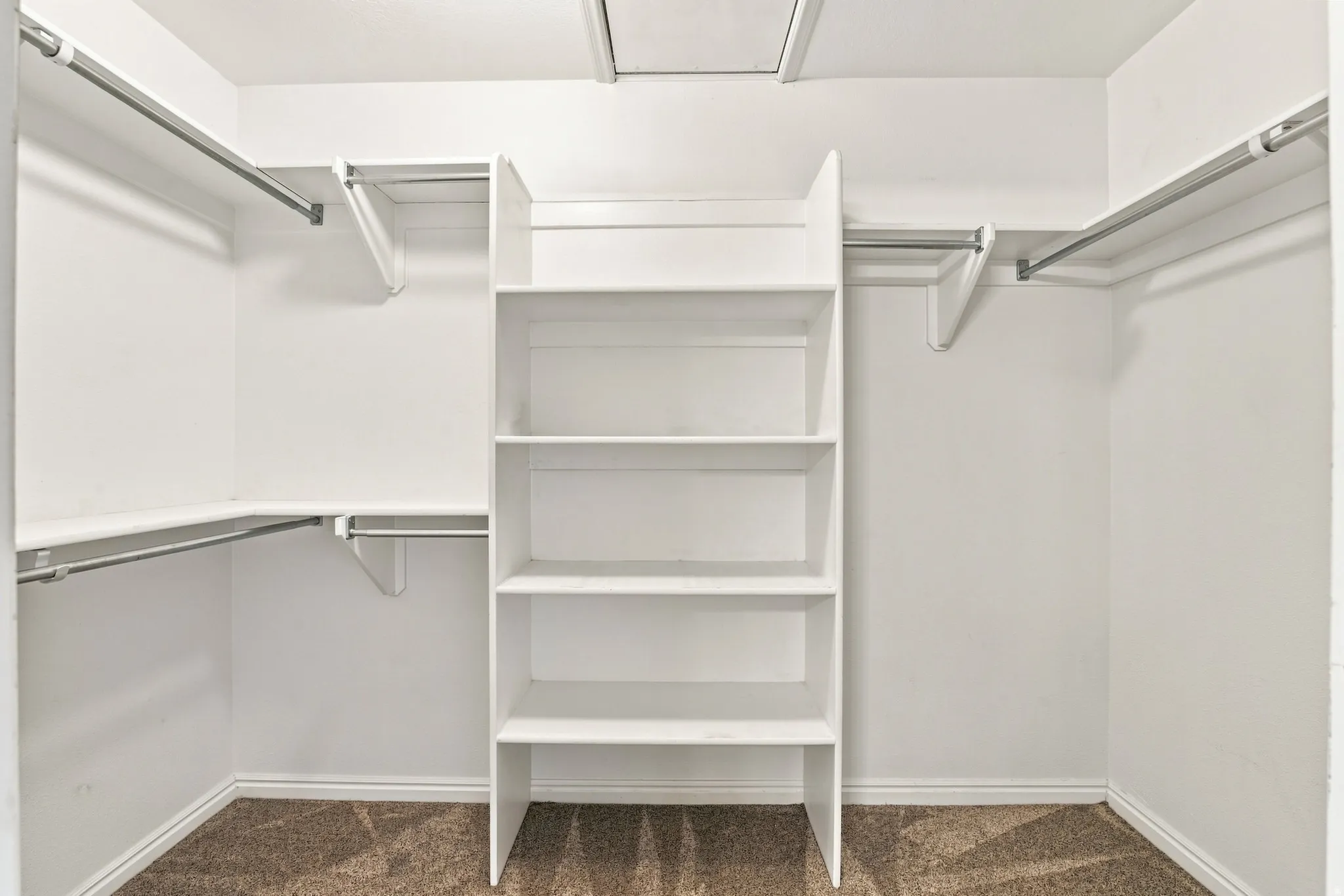 Built-in shelving, multiple hanging rods, and an overhead access panel