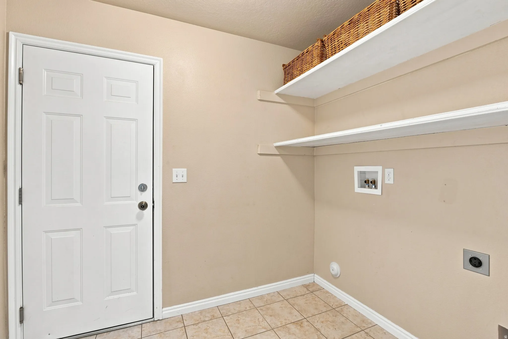 Laundry area featuring tile flooring, a paneled door, built-in shelving, and a dryer vent
