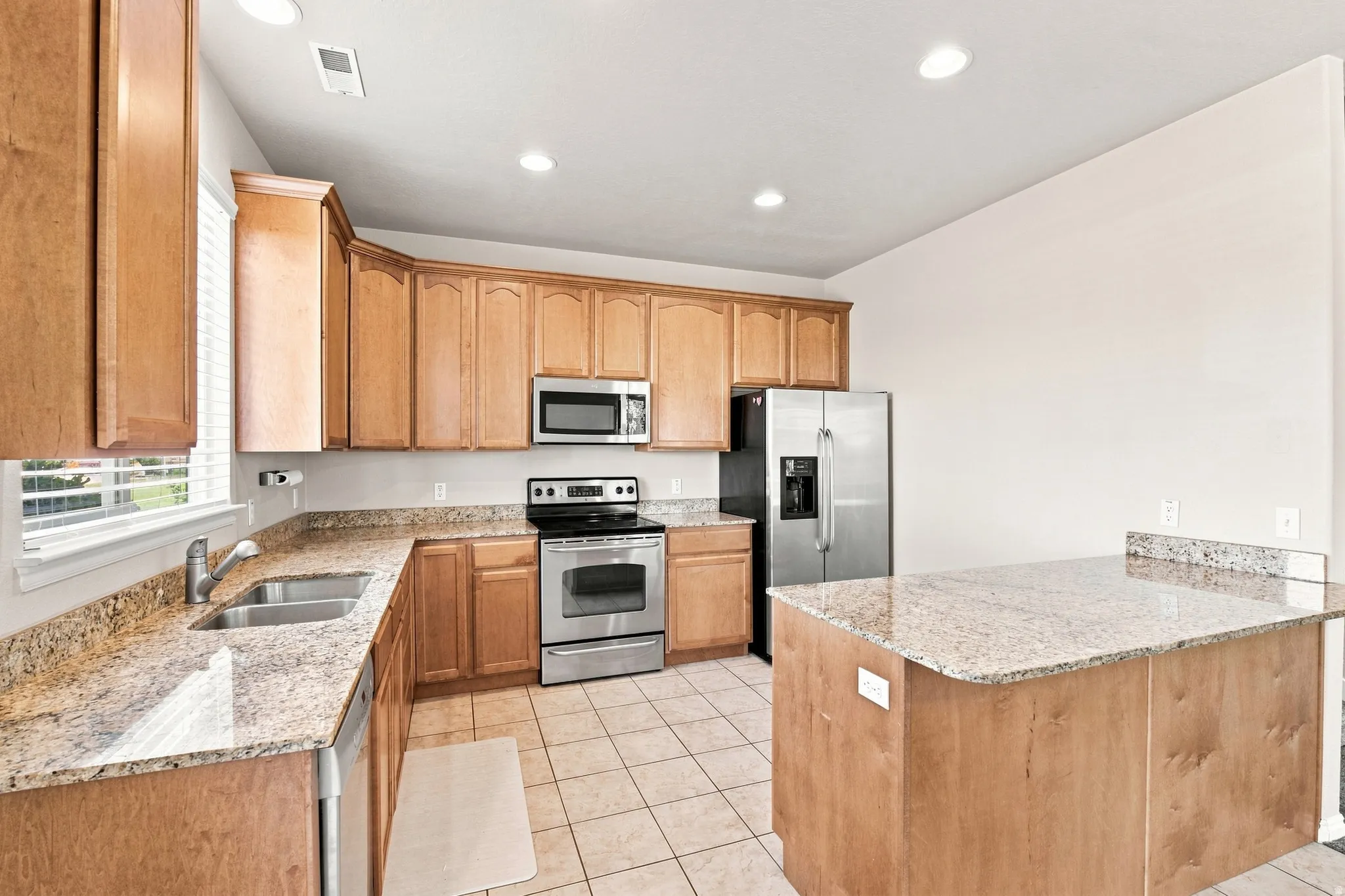 Kitchen featuring wood cabinetry, stainless steel appliances, granite countertops, a double basin sink, and ceramic tile flooring
