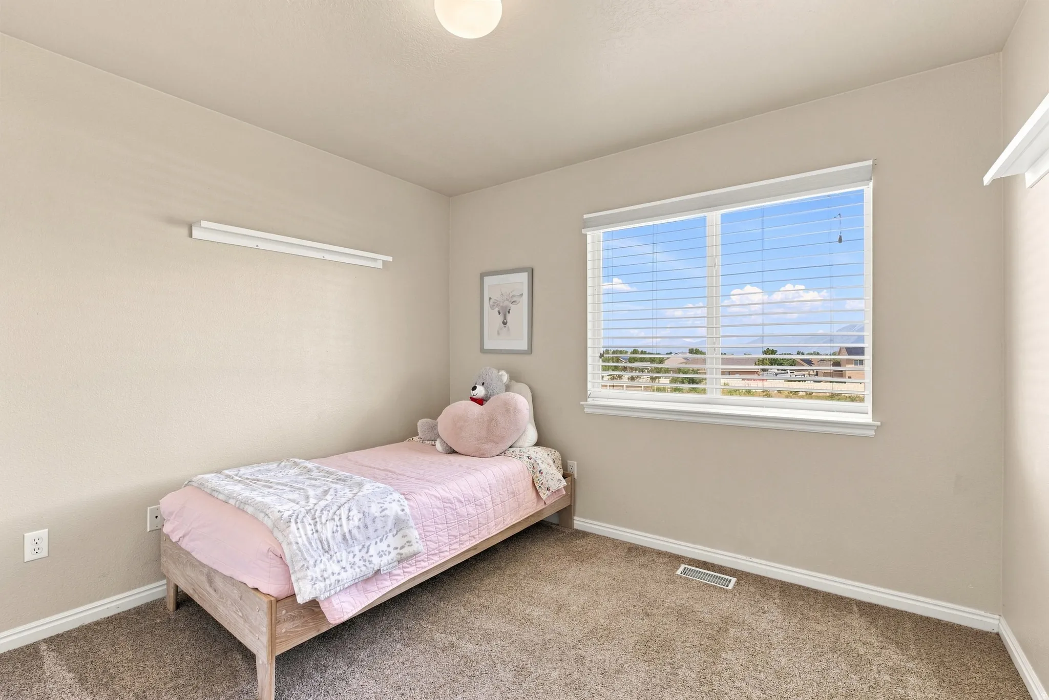 Neutral-toned walls with a single window featuring horizontal blinds
