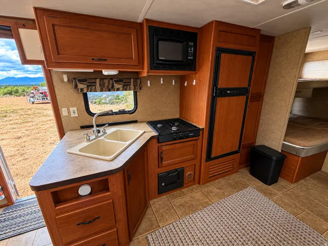 Compact kitchen featuring a dual-basin sink, gas stovetop, microwave, and refrigerator