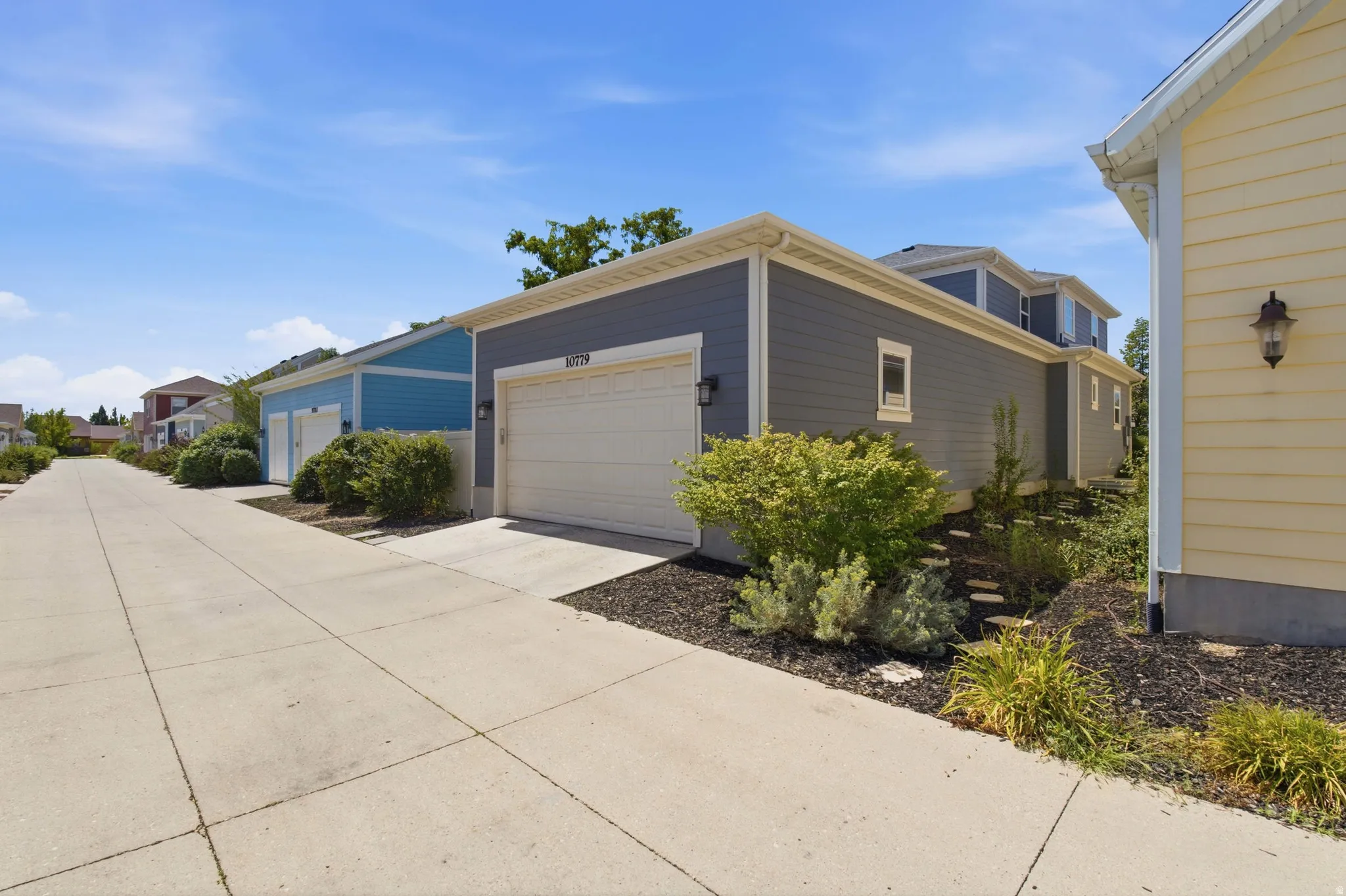 Attached two-car garage with overhead door, exterior wall sconces, and siding exterior