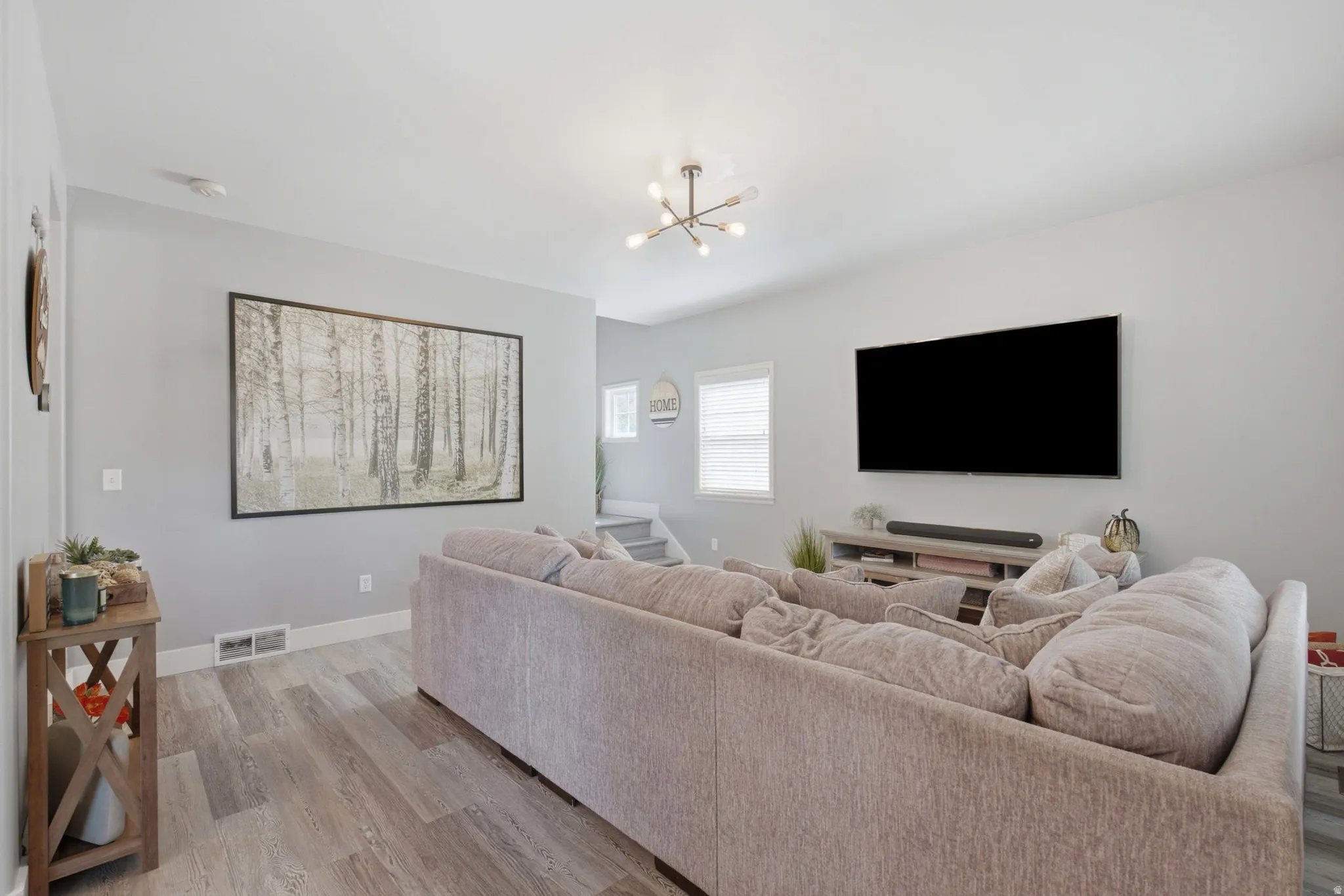 Wood-finish flooring, light gray wall tones, recessed lighting, and a modern ceiling light fixture