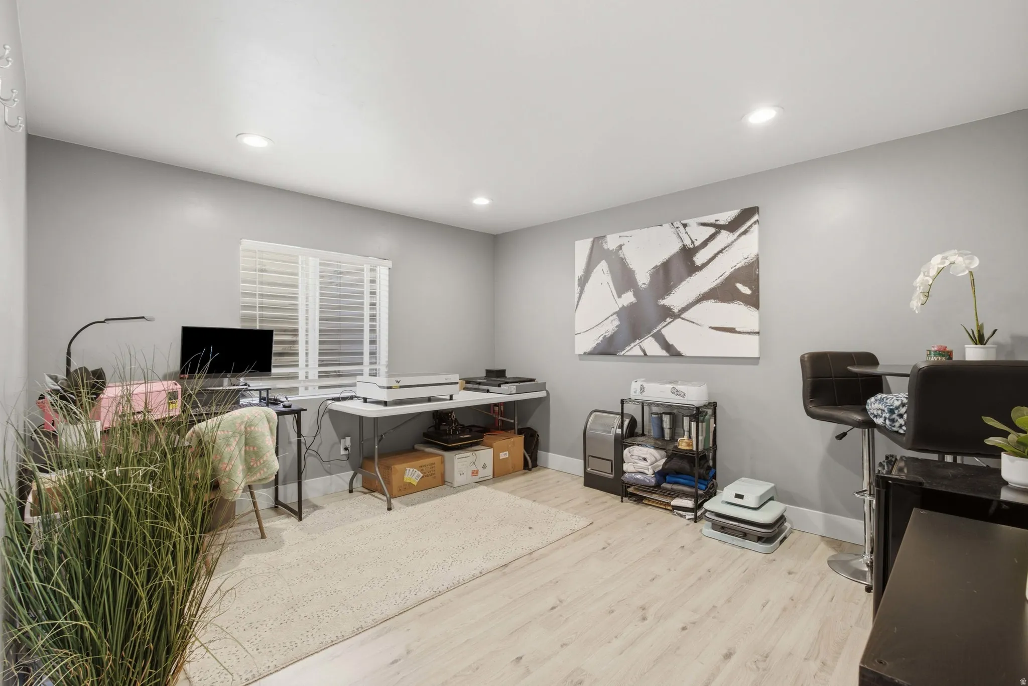 A second living room space that also can be used as an office, play area, or work out room. Recessed lighting, light wood-finish flooring, and a single window with horizontal blinds