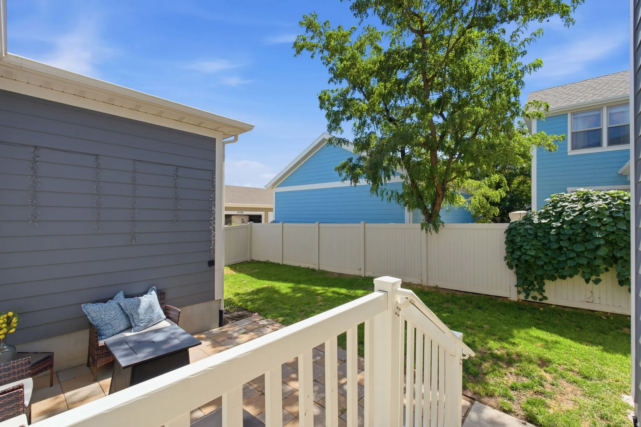 Private outdoor space featuring a paved patio and a grassy area, fully enclosed with a tall privacy fence.
