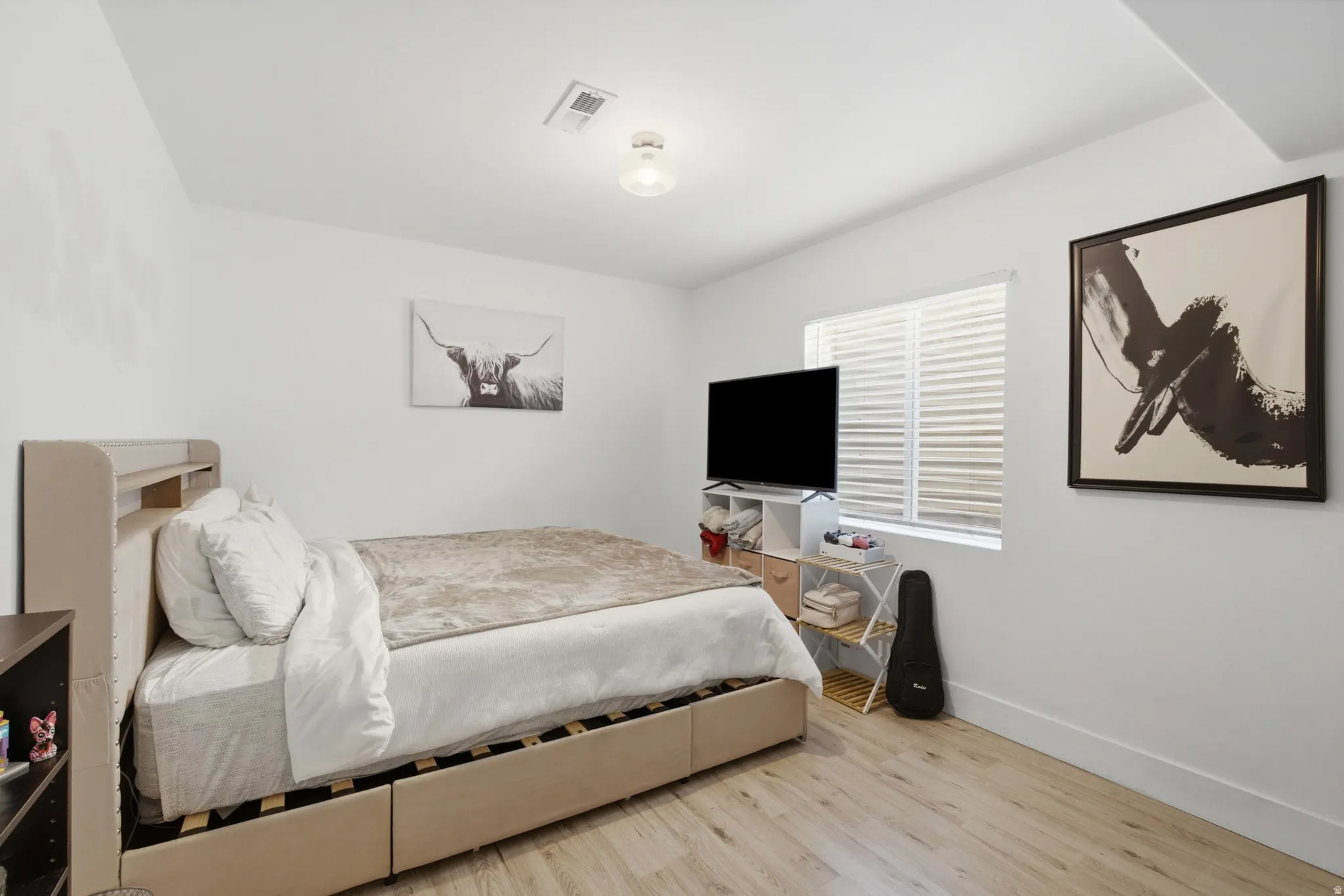 Light wood-finish flooring, white walls, and a single window with horizontal blinds