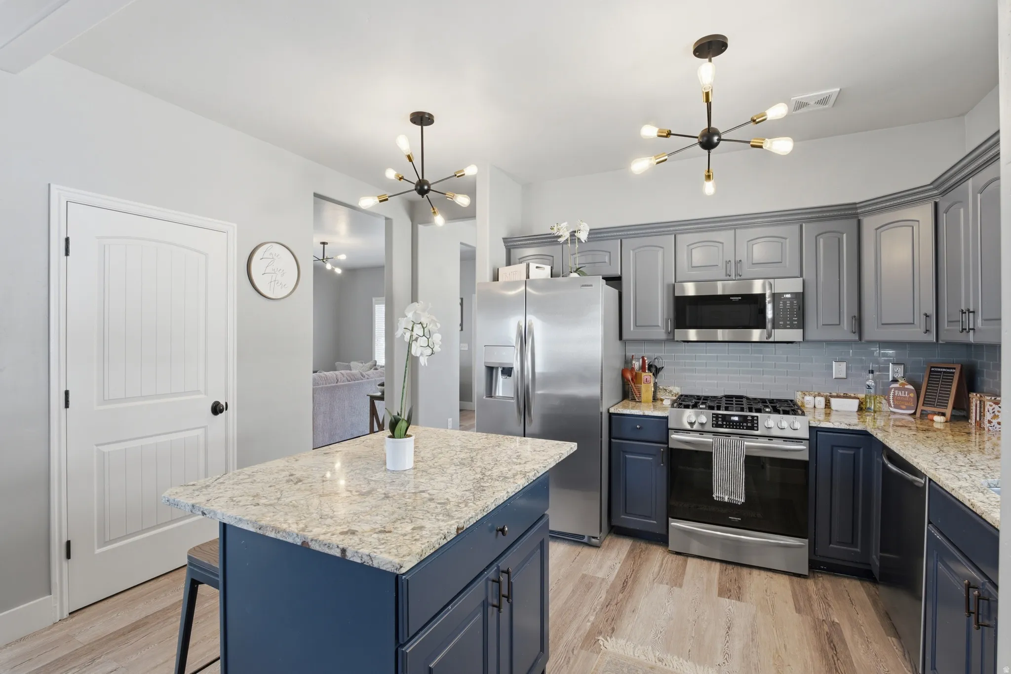 Kitchen featuring light-toned wood-finish flooring, a central island with a light-toned countertop, and dual-toned cabinetry