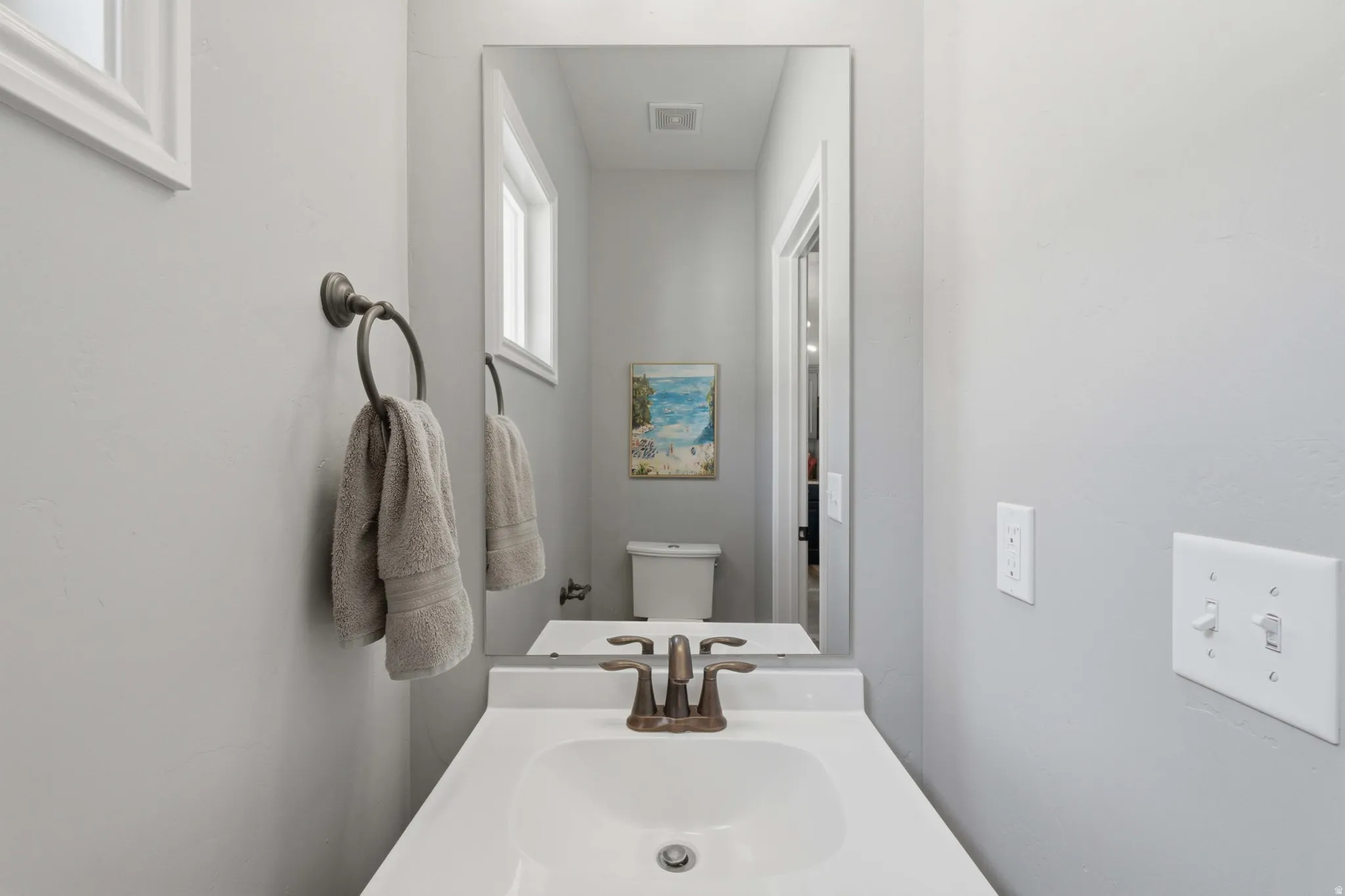 Integrated single-basin vanity with a bronze-finish faucet, paired with a large wall-mounted mirror