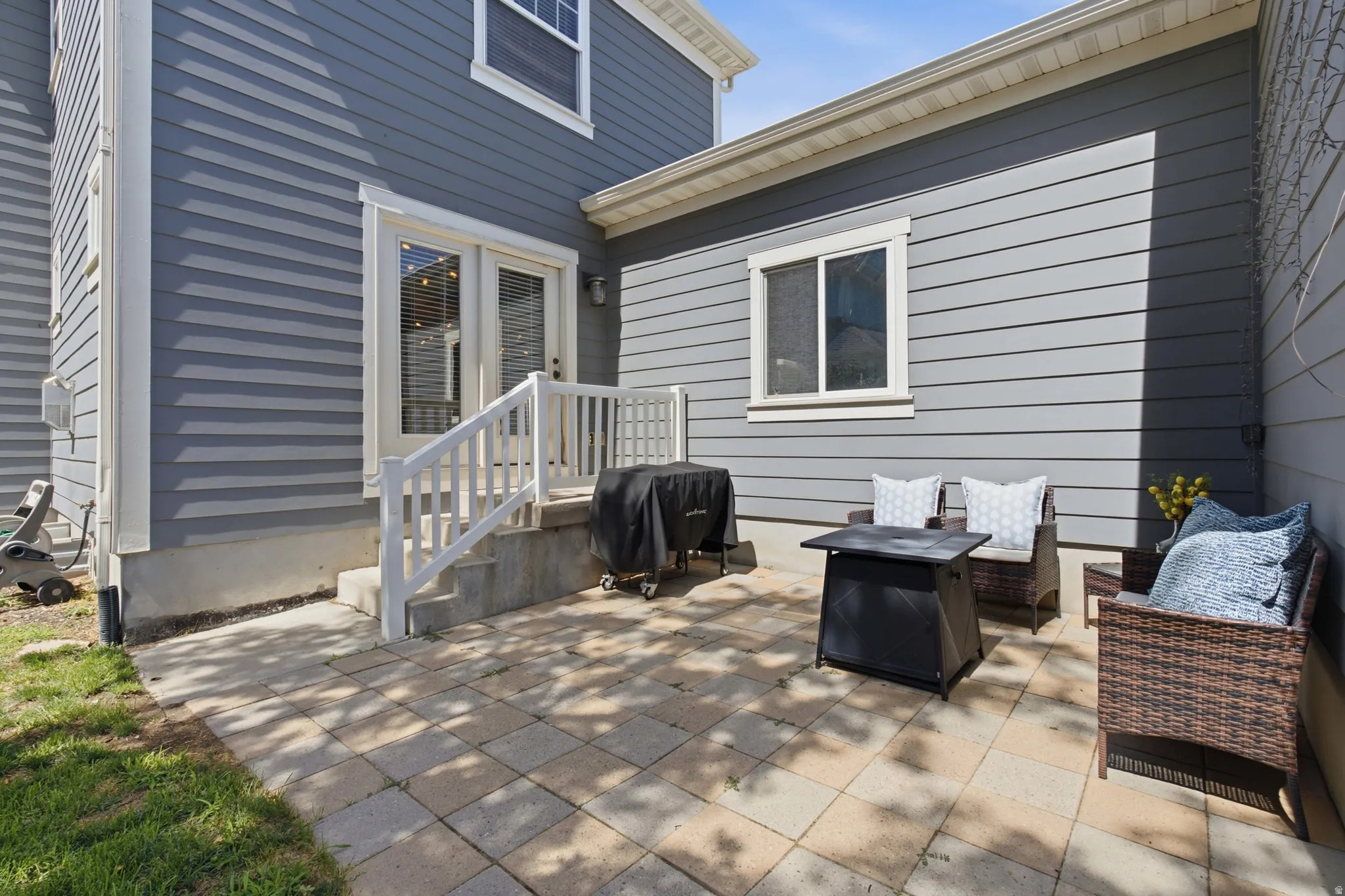 Paved patio with paver stones, white railing, and exterior French doors