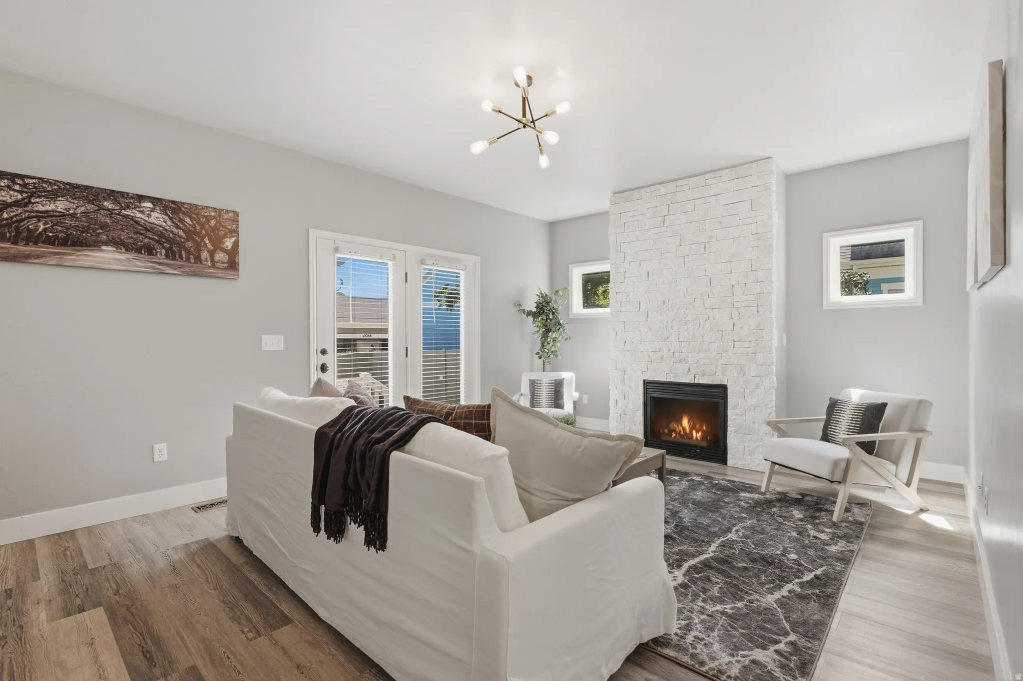 White brick fireplace with an integrated firebox, wood-finish flooring, recessed lighting, and white French doors