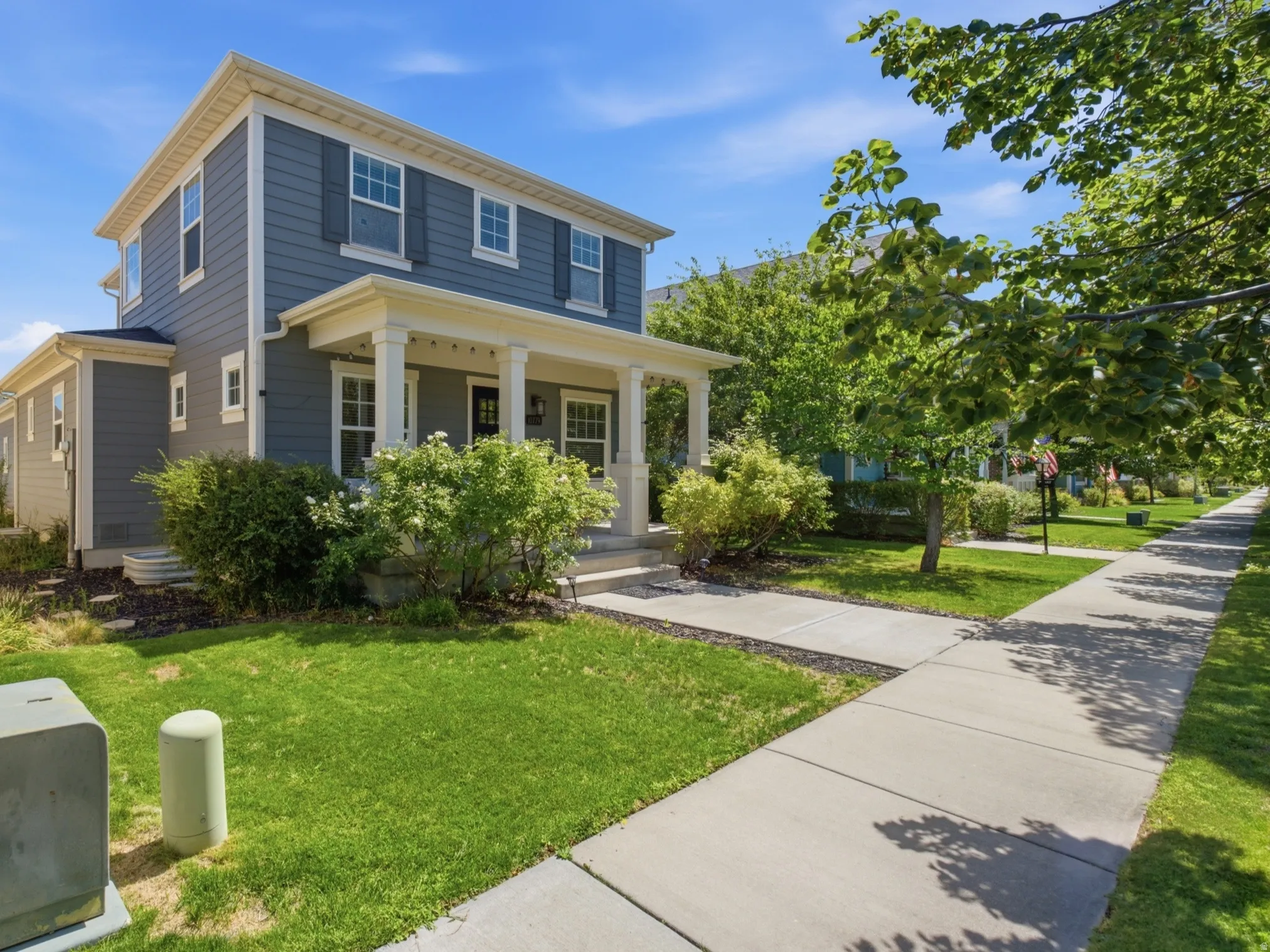 Two-story residence featuring blue siding with white trim, a covered front porch with white columns, and a concrete walkway