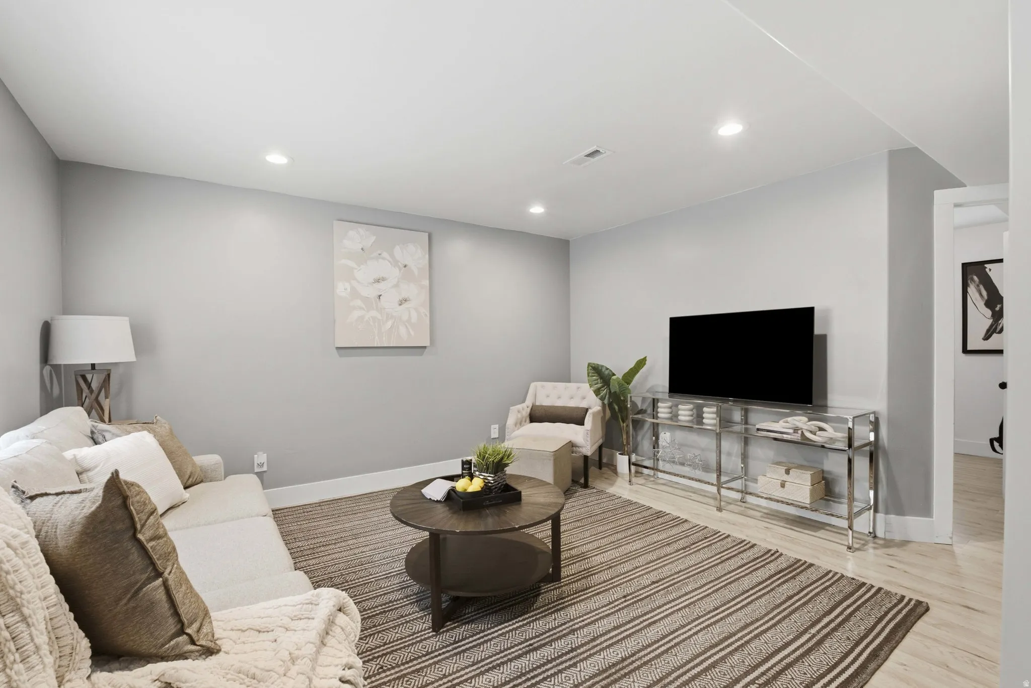 Recessed lighting, light wood-finish flooring, white trim, light gray walls, and an open doorway