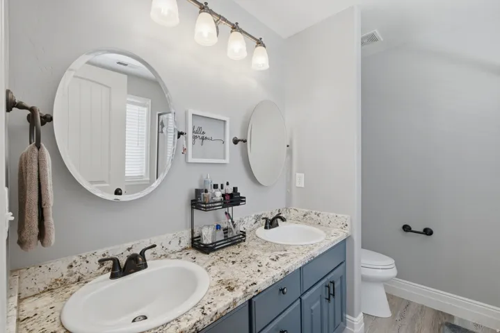 Owners ensuite with dual vanity sinks, granite-style countertop, and dark-finish cabinetry