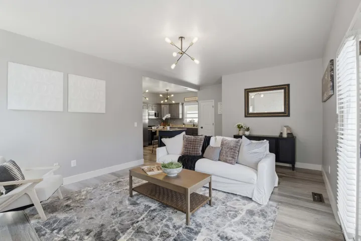 Open-concept living area with light gray walls, wood-finish flooring, and a contemporary ceiling fixture