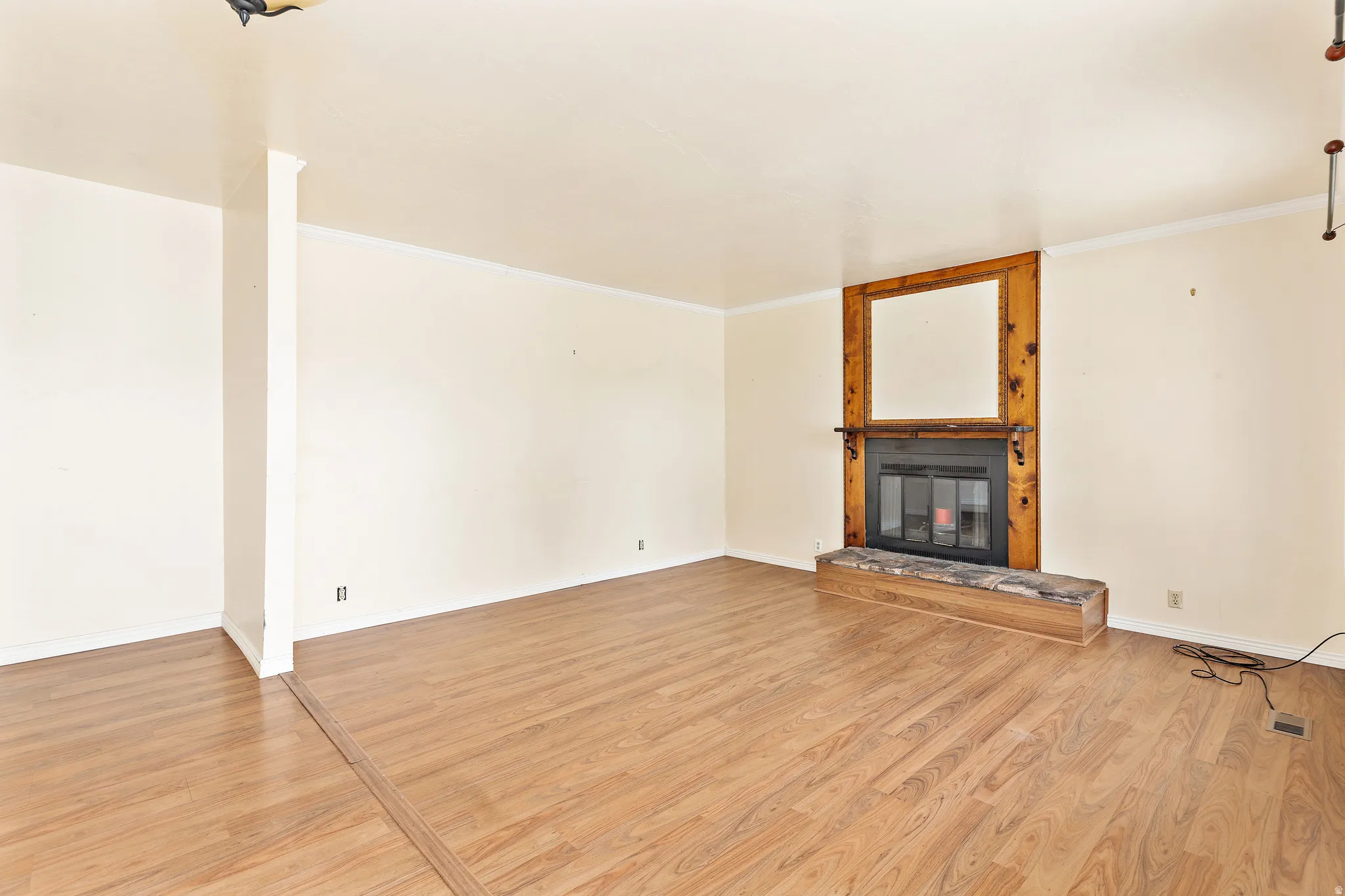 Spacious interior with wood-finish flooring, a built-in fireplace featuring a wood surround, and a stone hearth