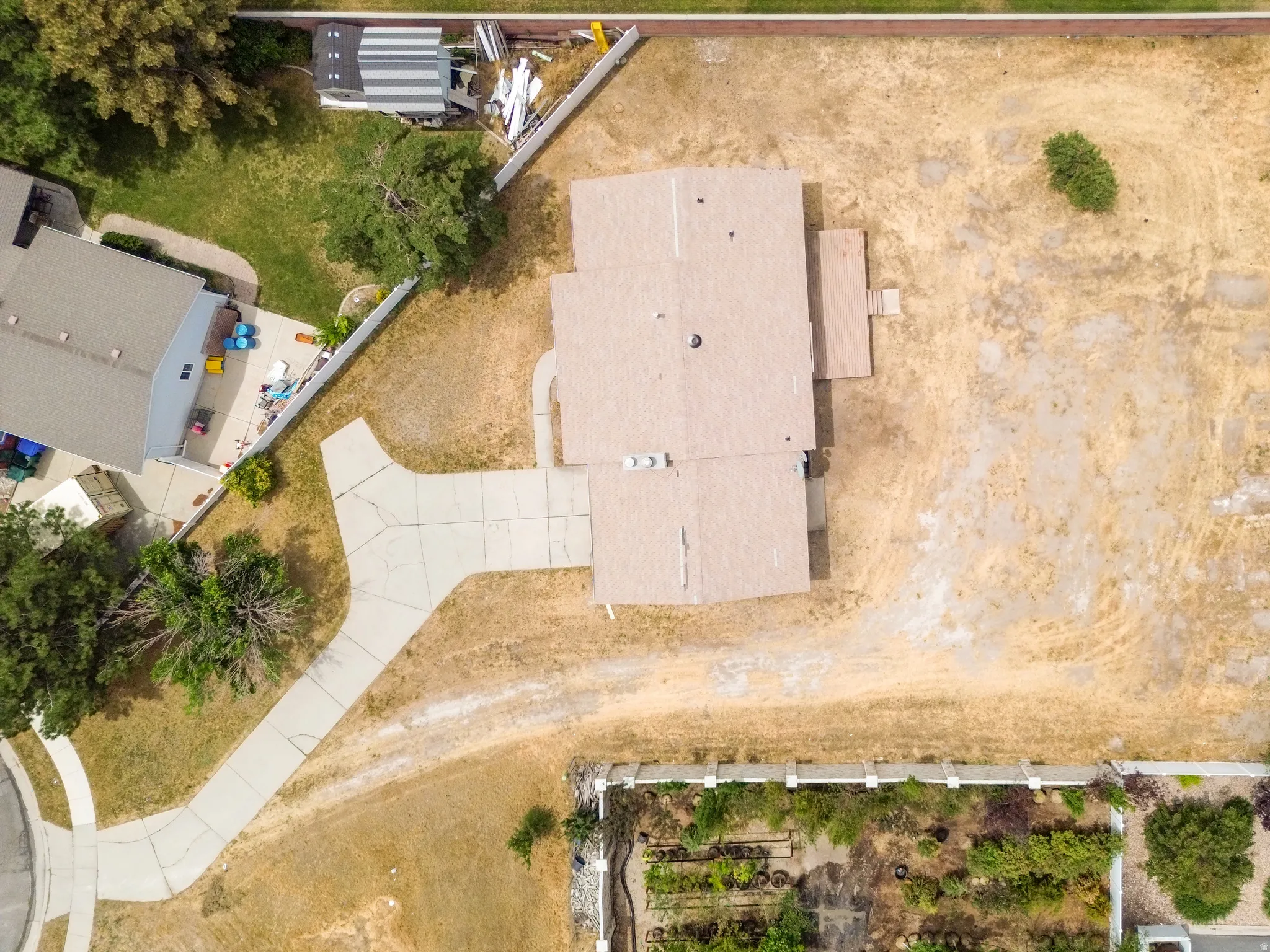 Extensive lot featuring a paved driveway, a large roof structure, and surrounding open land