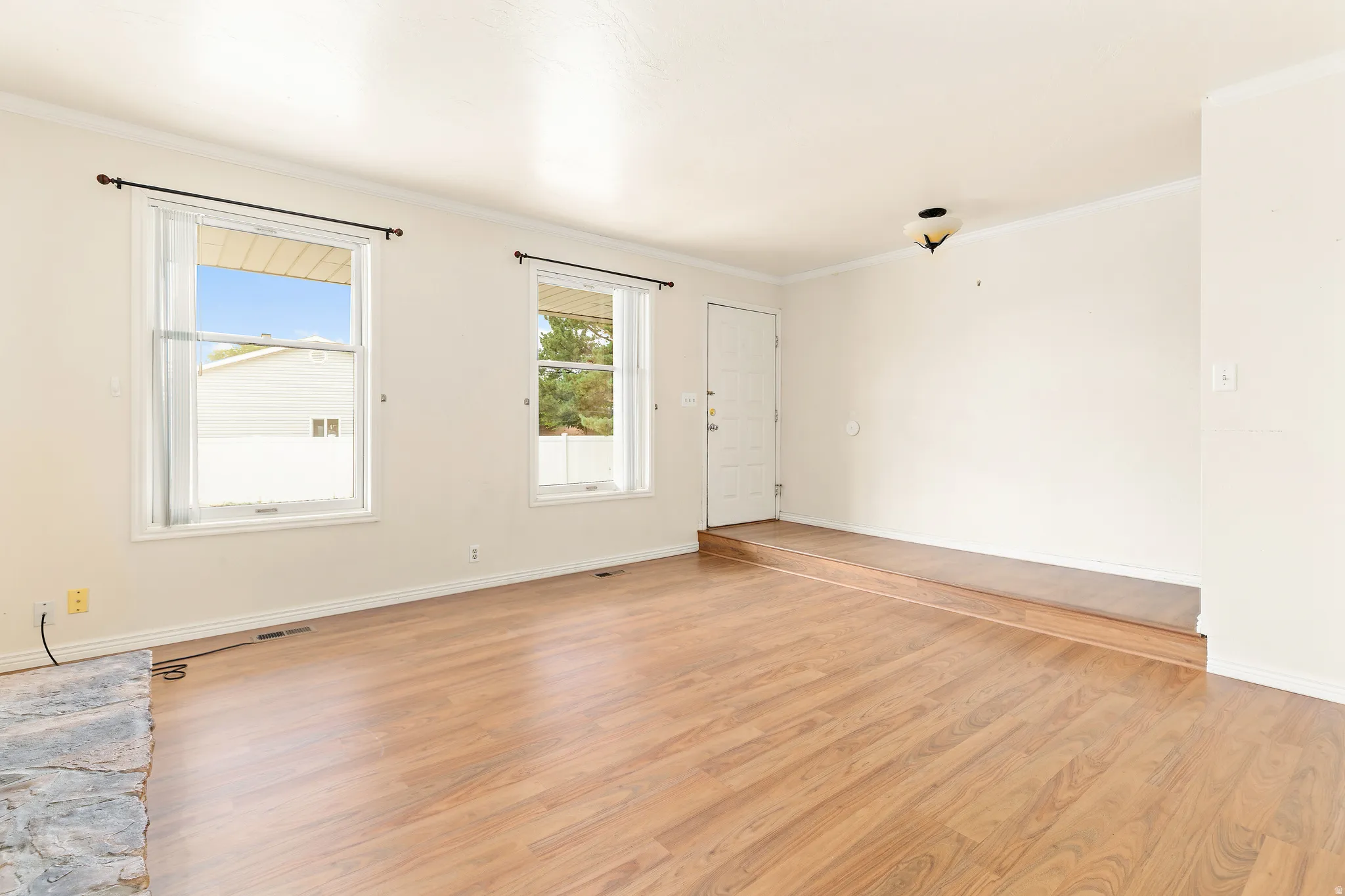 Wood-finish flooring, white walls, and crown molding