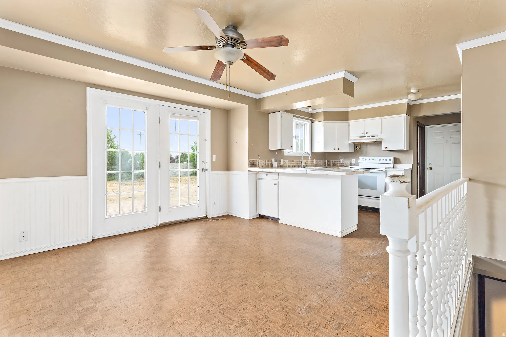 Open-concept living area with wood-finish flooring, white kitchen cabinetry, and built-in island