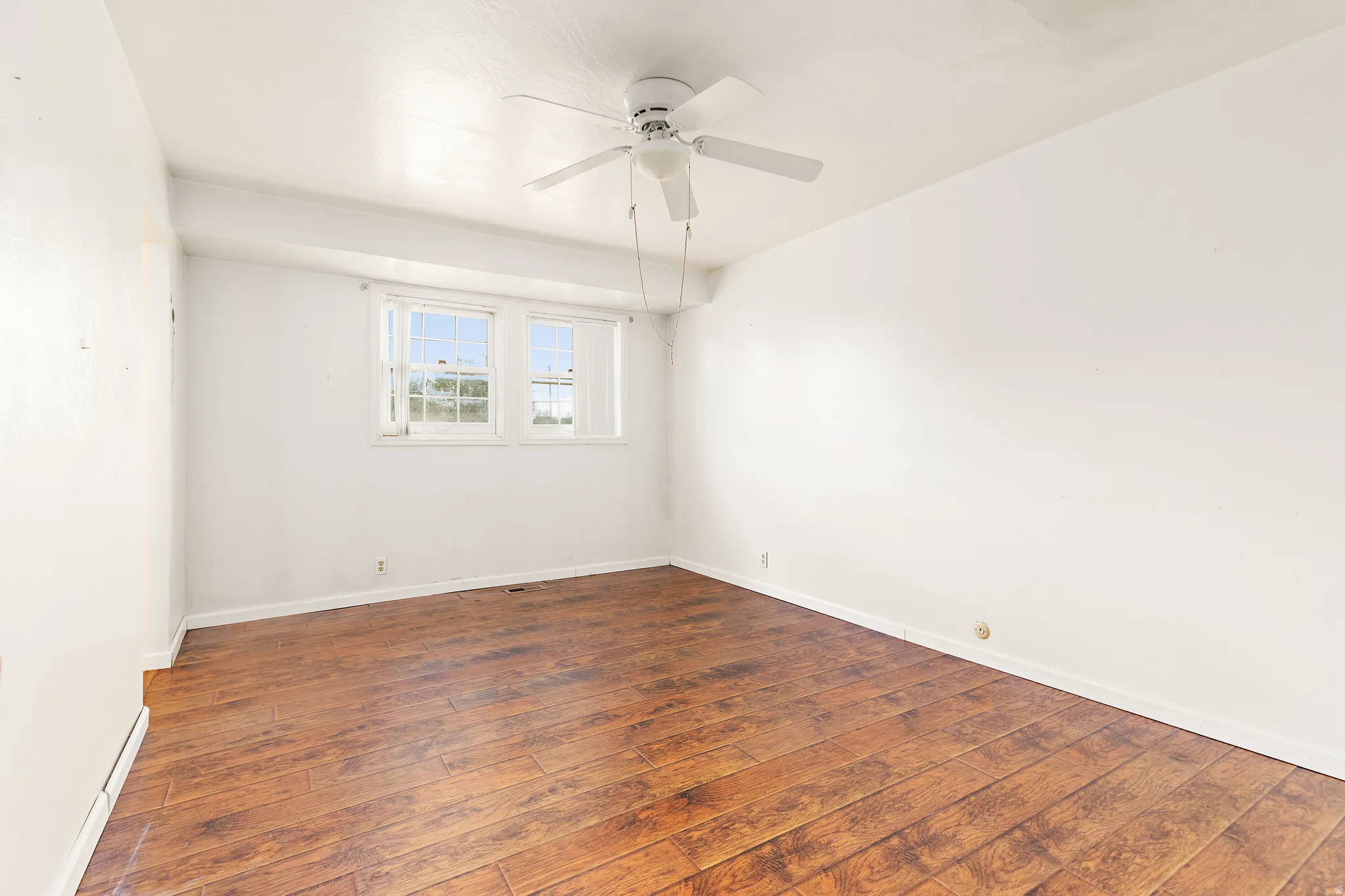 Wood-finish flooring, white walls, and a ceiling fan with integrated lighting