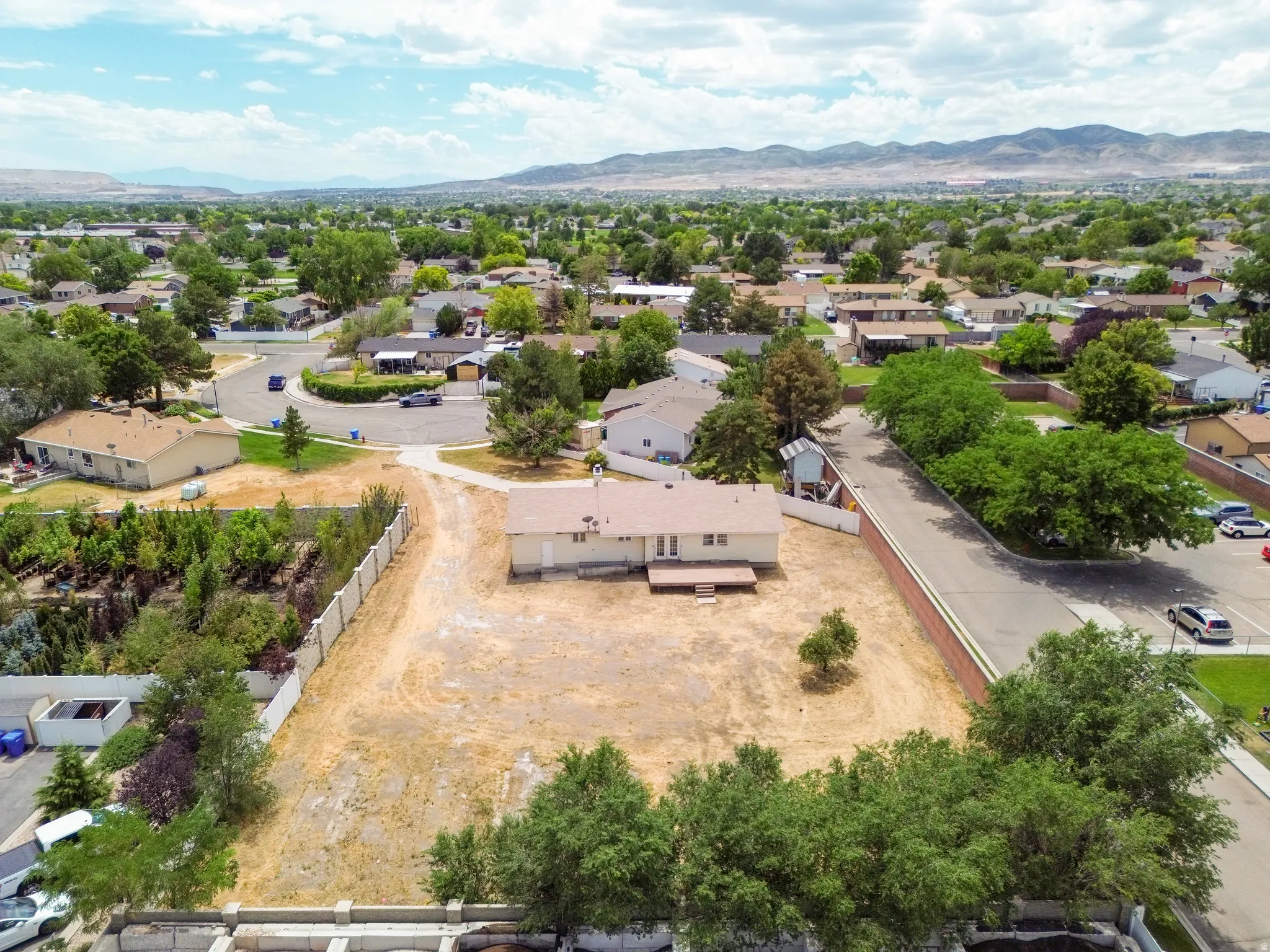 Expansive lot with single-story residence, featuring a wood deck and surrounding landscape