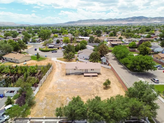 Expansive lot with single-story residence, featuring a wood deck and surrounding landscape
