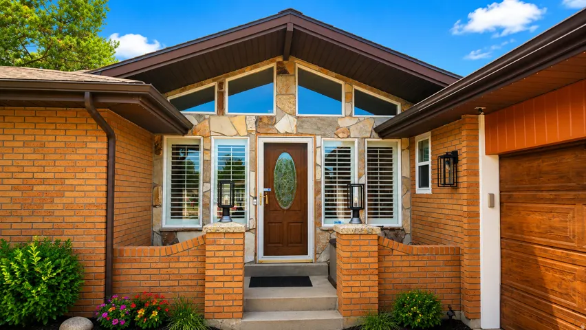 Brick and stone exterior with a prominent wooden entry door, accented by angular transom windows