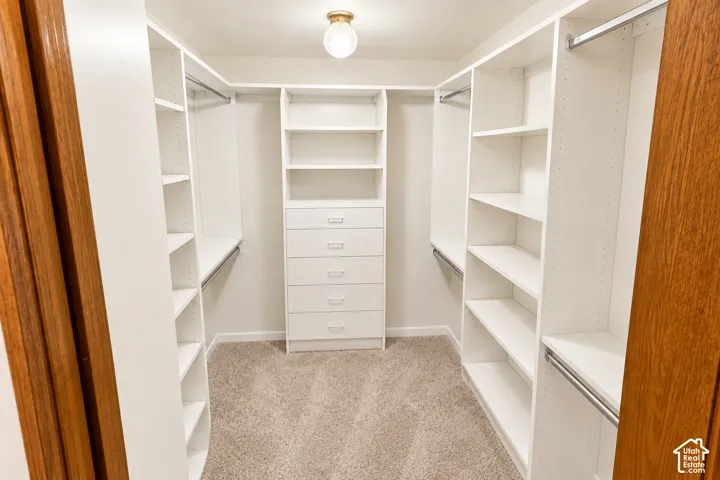 Walk-in closet with built-in shelving, hanging rods, and a central dresser unit