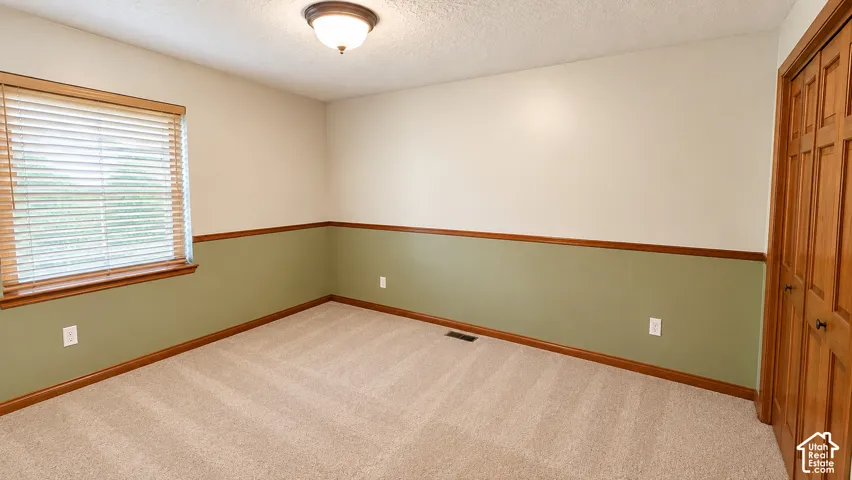 Recessed lighting fixture, textured ceiling, two-tone wall paint, wood-finish trim, and carpet flooring