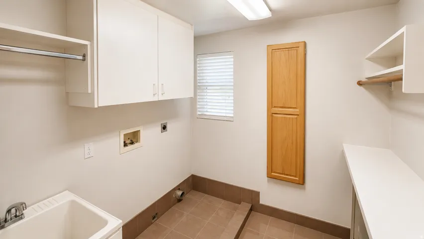 Utility room featuring white cabinetry, a built-in sink, and tiled flooring
