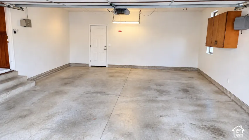 Spacious garage featuring a finished concrete floor, built-in storage cabinetry, and a service door