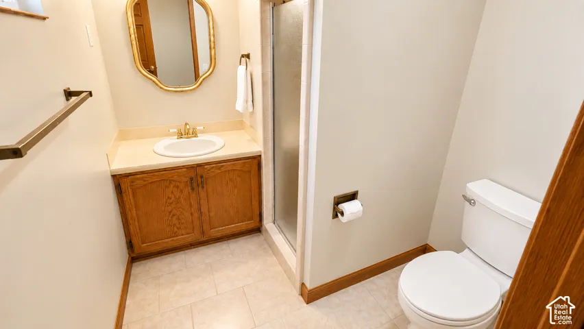 Built-in wood vanity with single basin, countertop, and an enclosed shower with a glass door