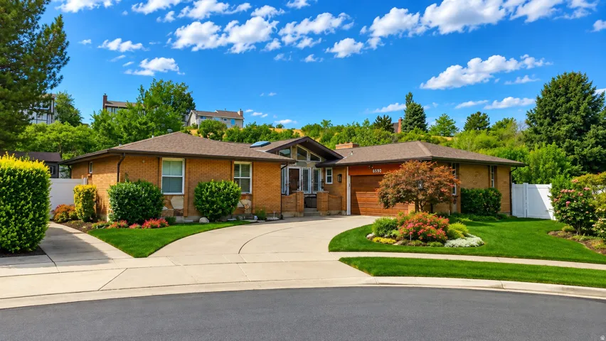 Brick exterior with stone accents, a multi-pane front door, an attached garage, and a curved driveway