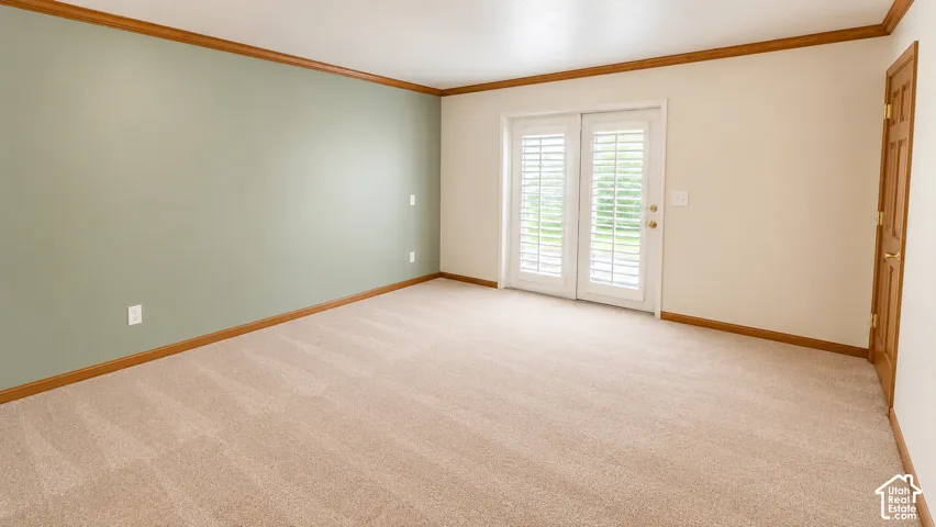 Wall-to-wall carpeting with wooden trim, neutral paint finishes, and double French doors with interior shutters