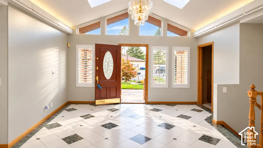 Entryway featuring a decorative tile floor, a chandelier, and a wood-paneled front door with an oval glass insert