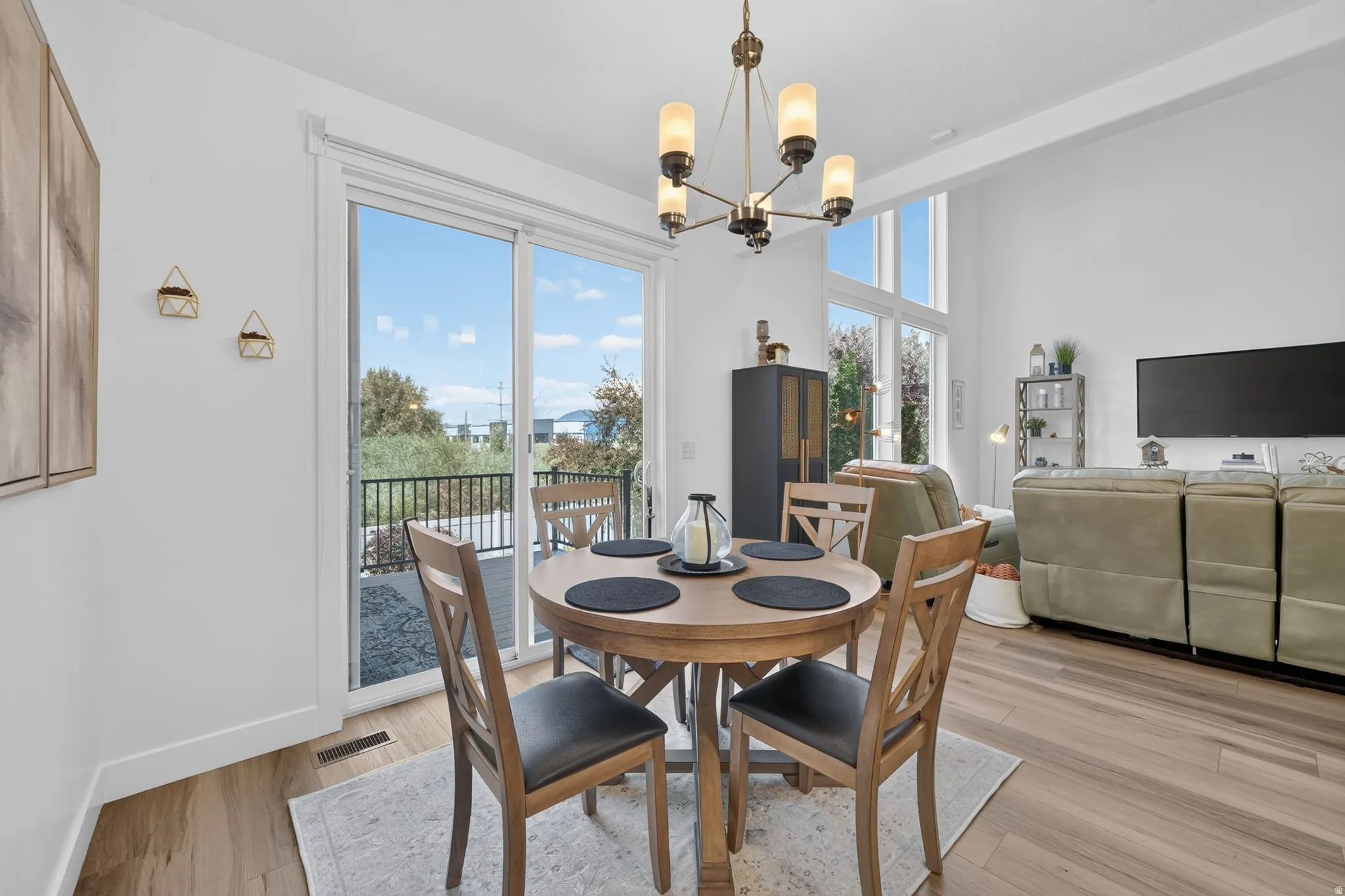 Open-concept living space with wood-finish flooring, a contemporary chandelier, and high ceilings