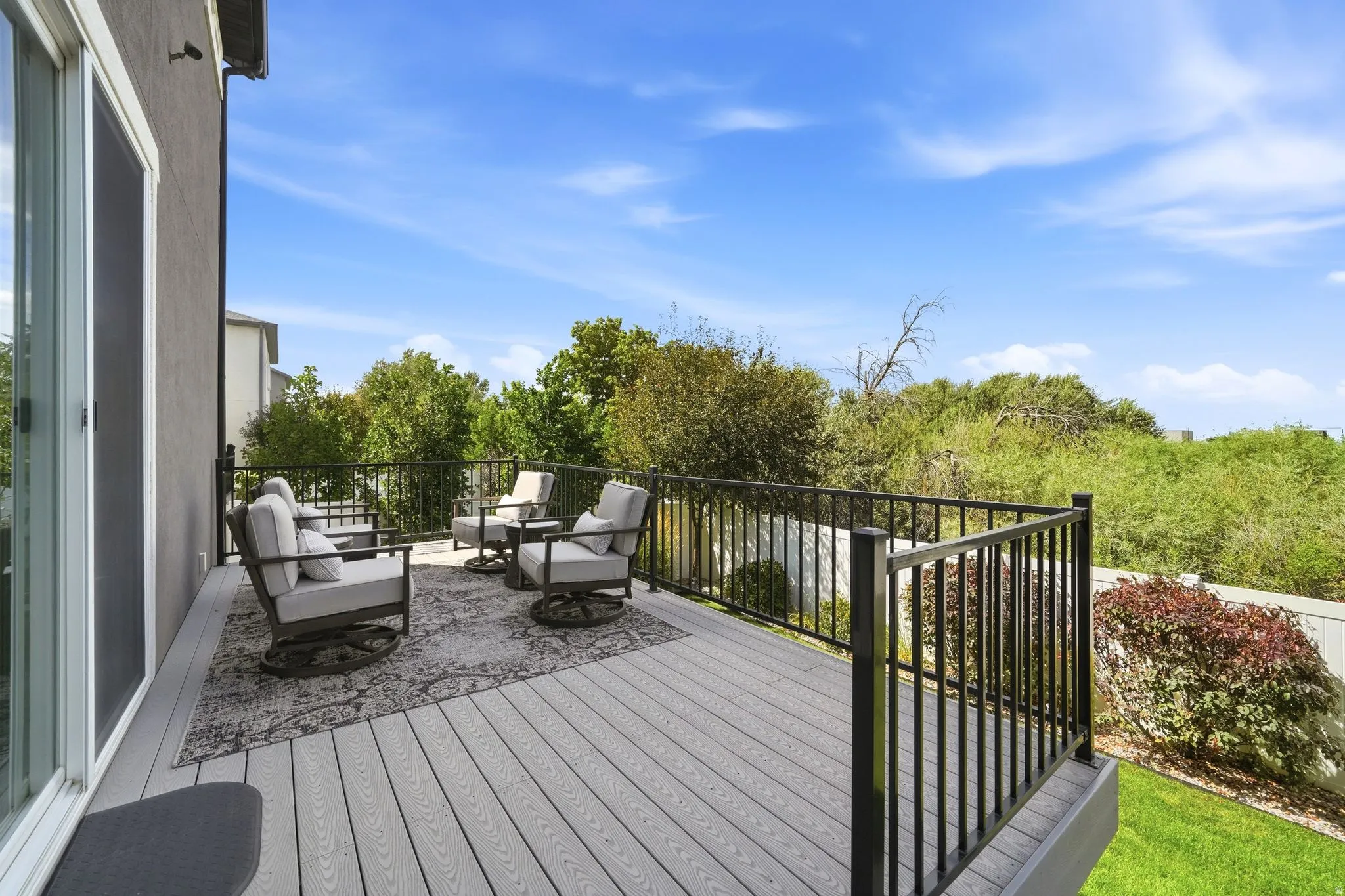 Expansive outdoor deck with composite decking, black metal railing, and direct access through a sliding glass door