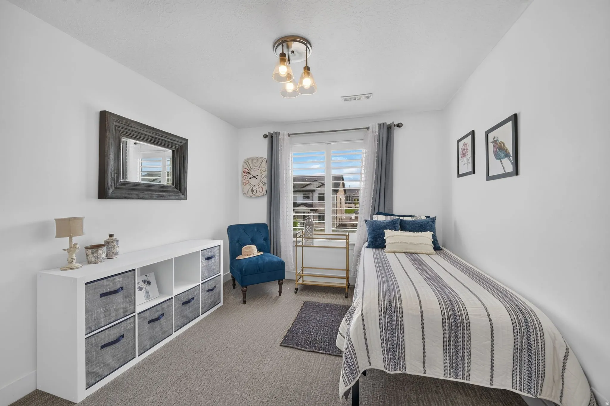 Recessed window with white blinds, overhead multi-bulb light fixture, wall-mounted mirror with a distressed wood frame, and wall-to-wall carpeting