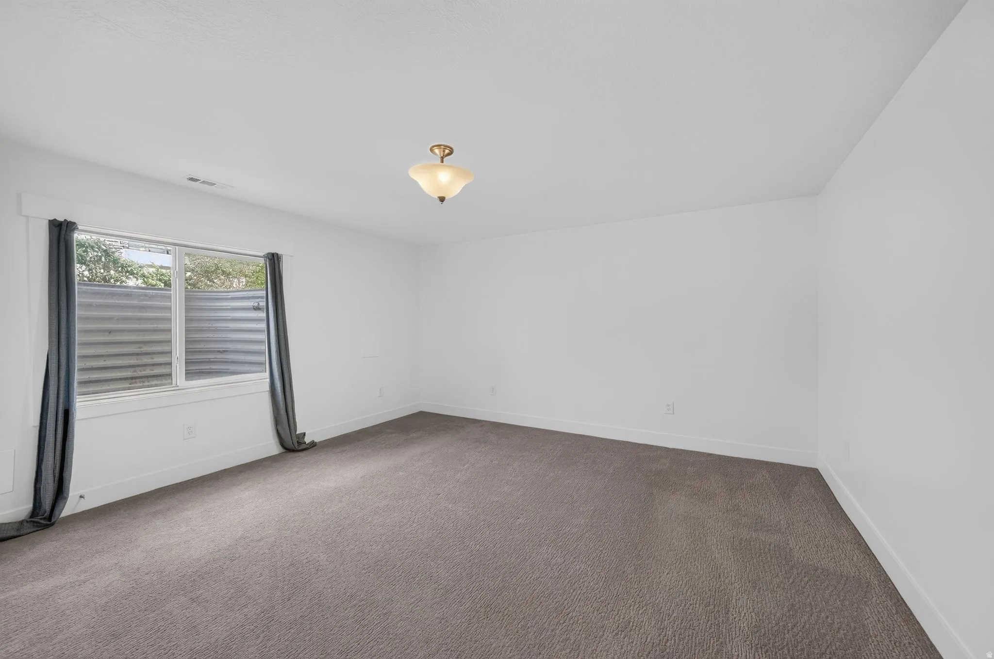 Recessed window with corrugated metal well, neutral carpeting, and a semi-flush mount ceiling light