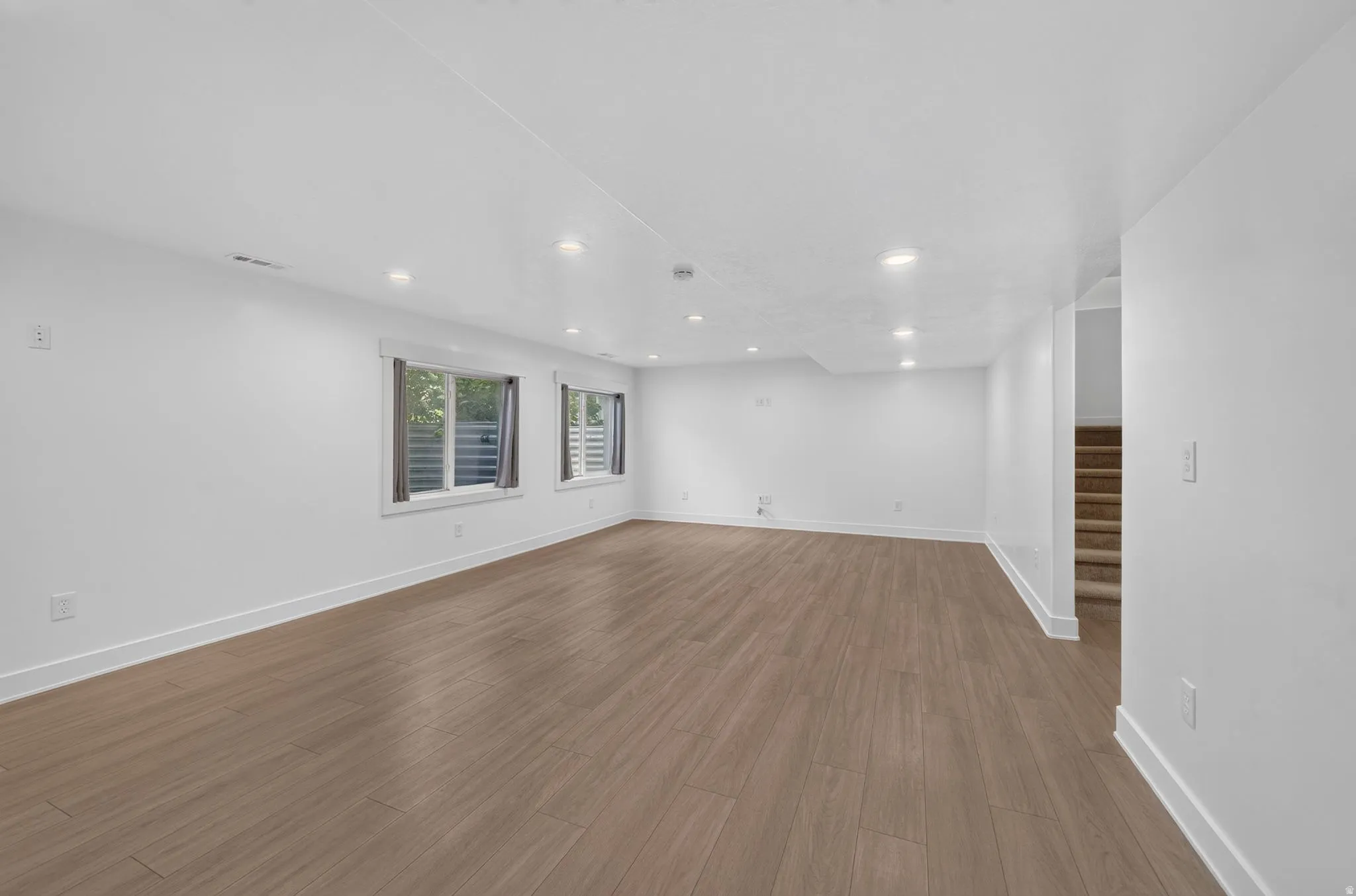 Basement Expansive open-concept room featuring wood-finish flooring, recessed lighting, and multiple windows
