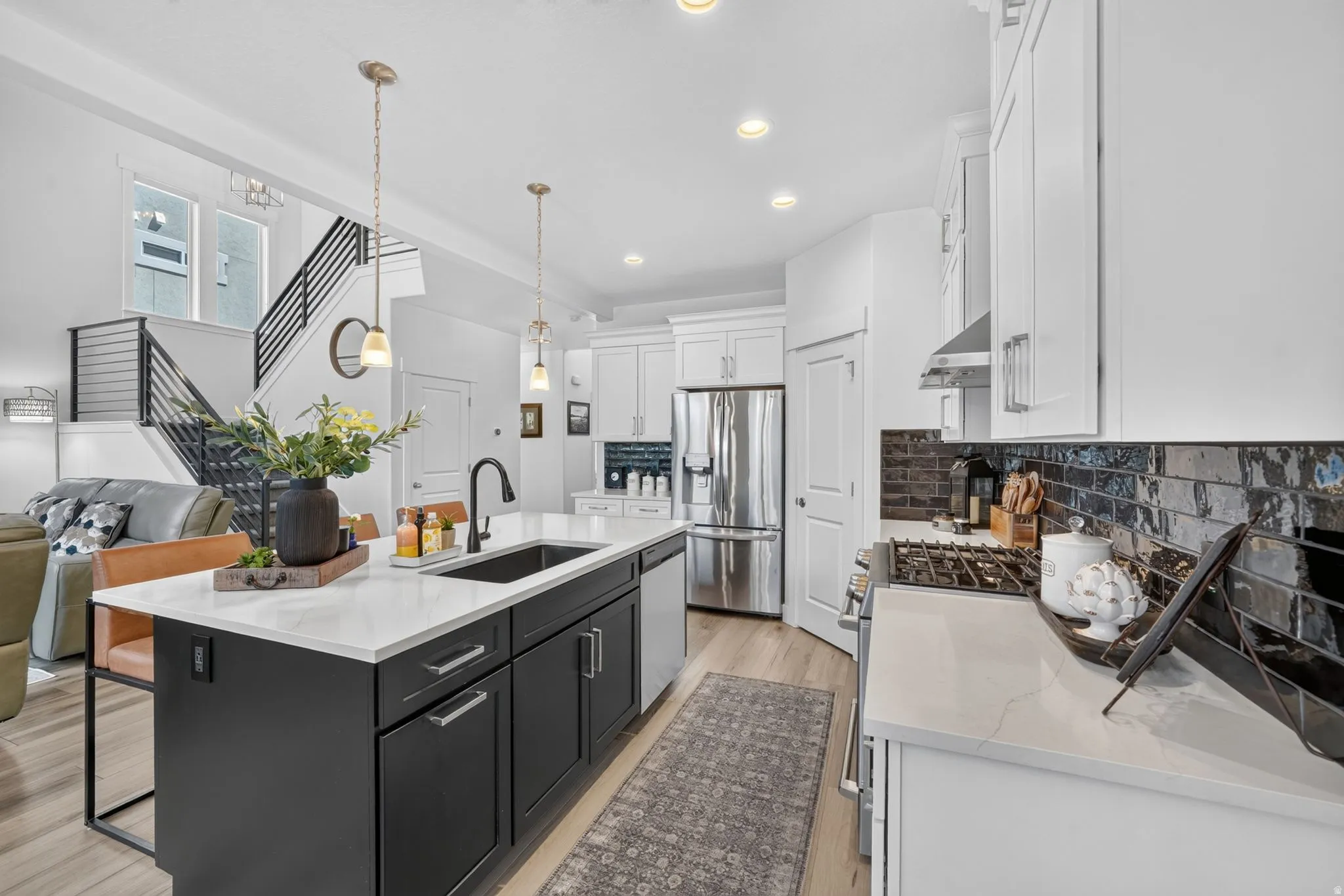 Kitchen featuring a central island with a built-in sink, white countertops, stainless steel appliances, and wood-finish flooring